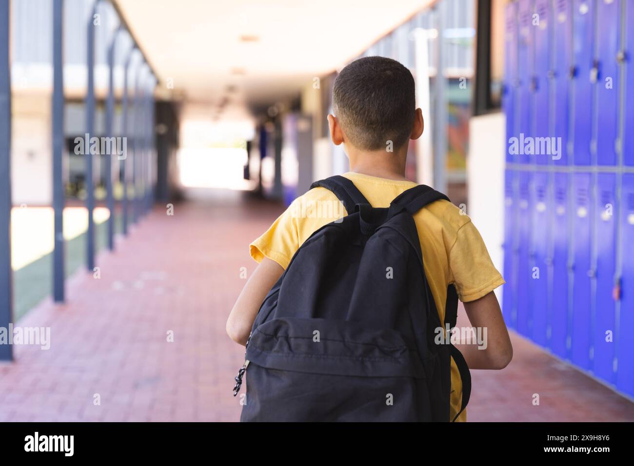 Un ragazzo birazziale cammina lungo un corridoio della scuola Foto Stock