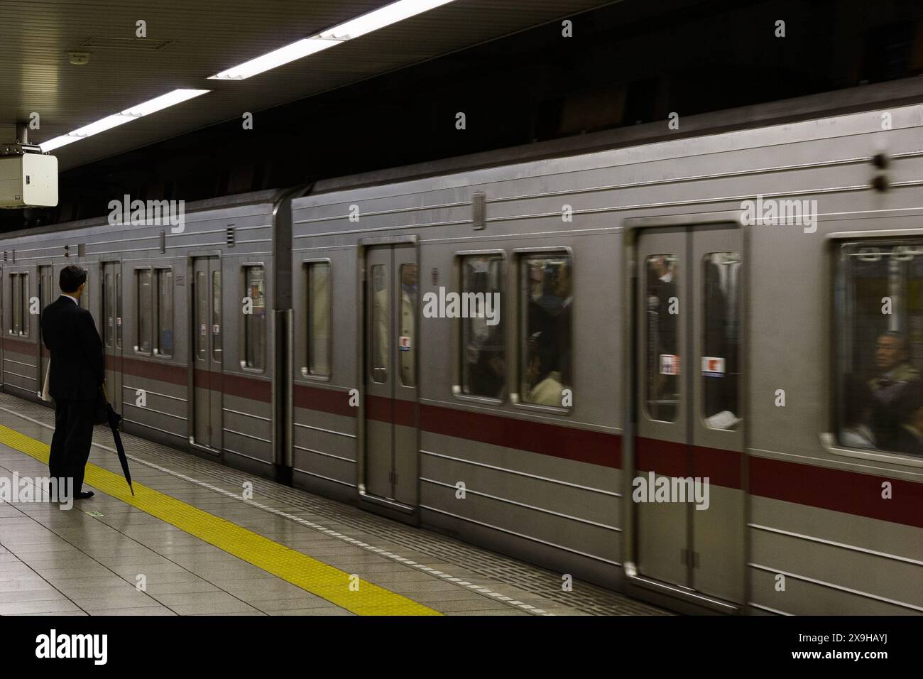 Un uomo d'affari o un venditore giapponese alla stazione di Sakurademon come treno pendolare della linea Yurakucho, Tobu 9000. Tokyo, Giappone Foto Stock