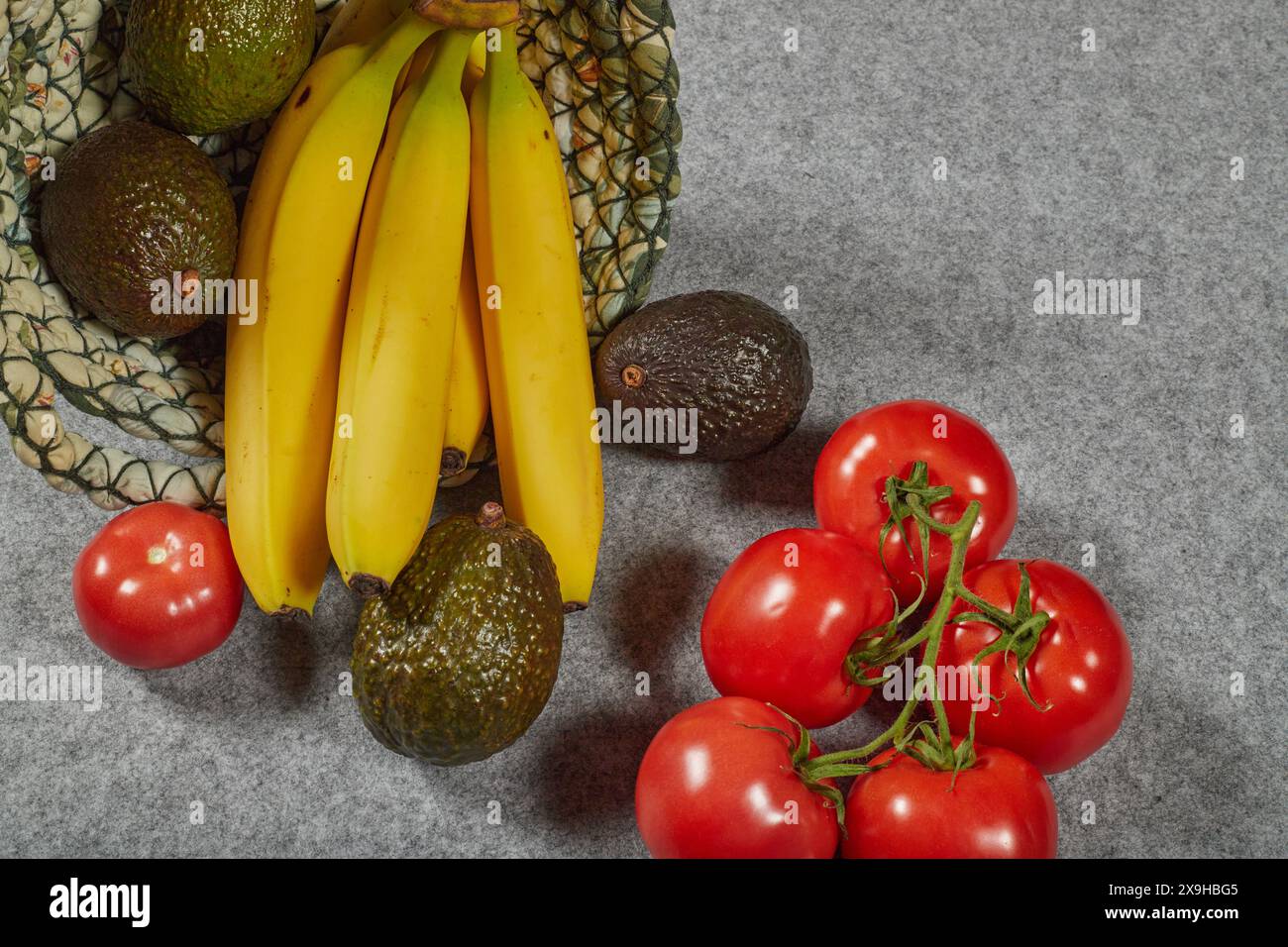 Alimenti biologici ricchi di potassio, avocado, banane e pomodori. Cibi salutari estivi in un cestino di lino!!! Foto Stock