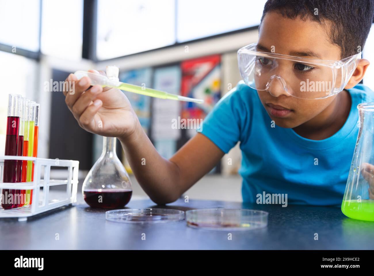 Ragazzo birazziale impegnato in un esperimento scientifico a scuola in classe Foto Stock