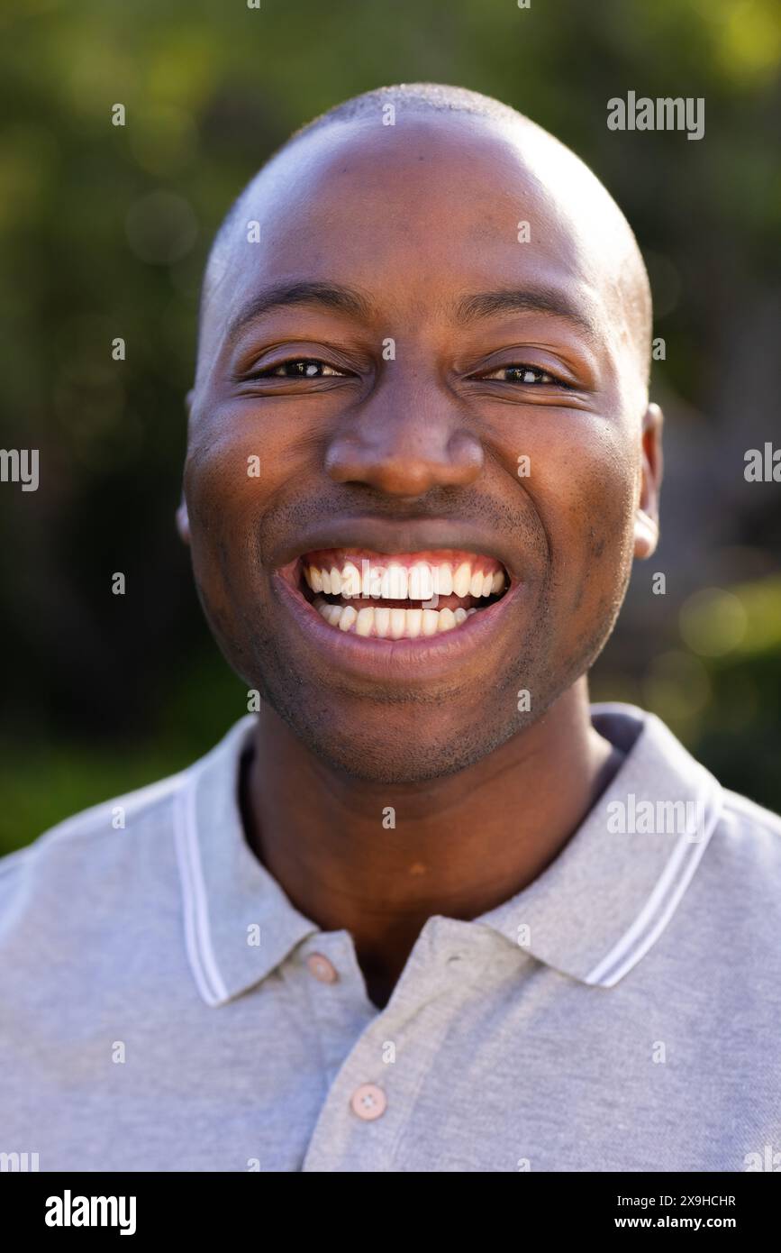 All'aperto, sorridente uomo afroamericano con polo grigia che si gode una giornata di sole Foto Stock