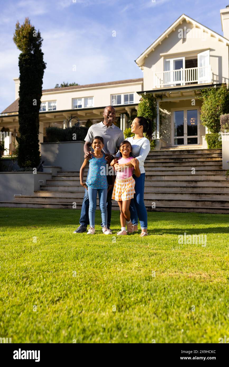 All'aperto, una famiglia diversificata di quattro persone che si trovano insieme su un prato verde lussureggiante e sorridente Foto Stock All'aperto, una famiglia diversificata di quattro persone che si trovano insieme su un prato verde lussureggiante e sorridente Foto Stock