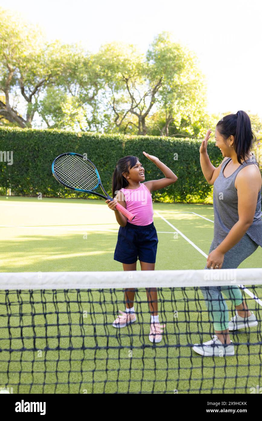 All'aperto, madre e figlia birazziali che giocano sul campo da tennis Foto Stock