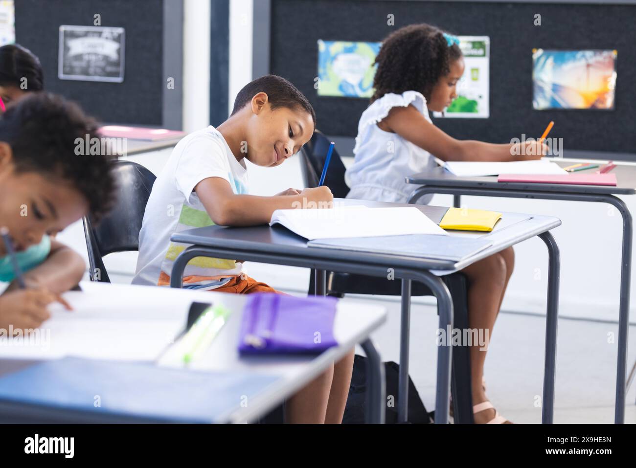 I bambini sono concentrati sul loro lavoro scolastico in una classe scolastica, sottolineando il concetto di istruzione Foto Stock