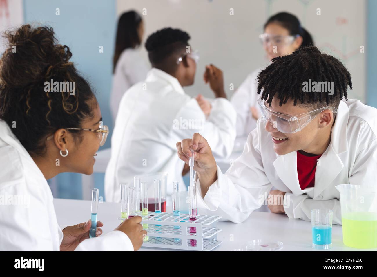 Studenti diversi si impegnano in un esperimento di chimica alle superiori Foto Stock