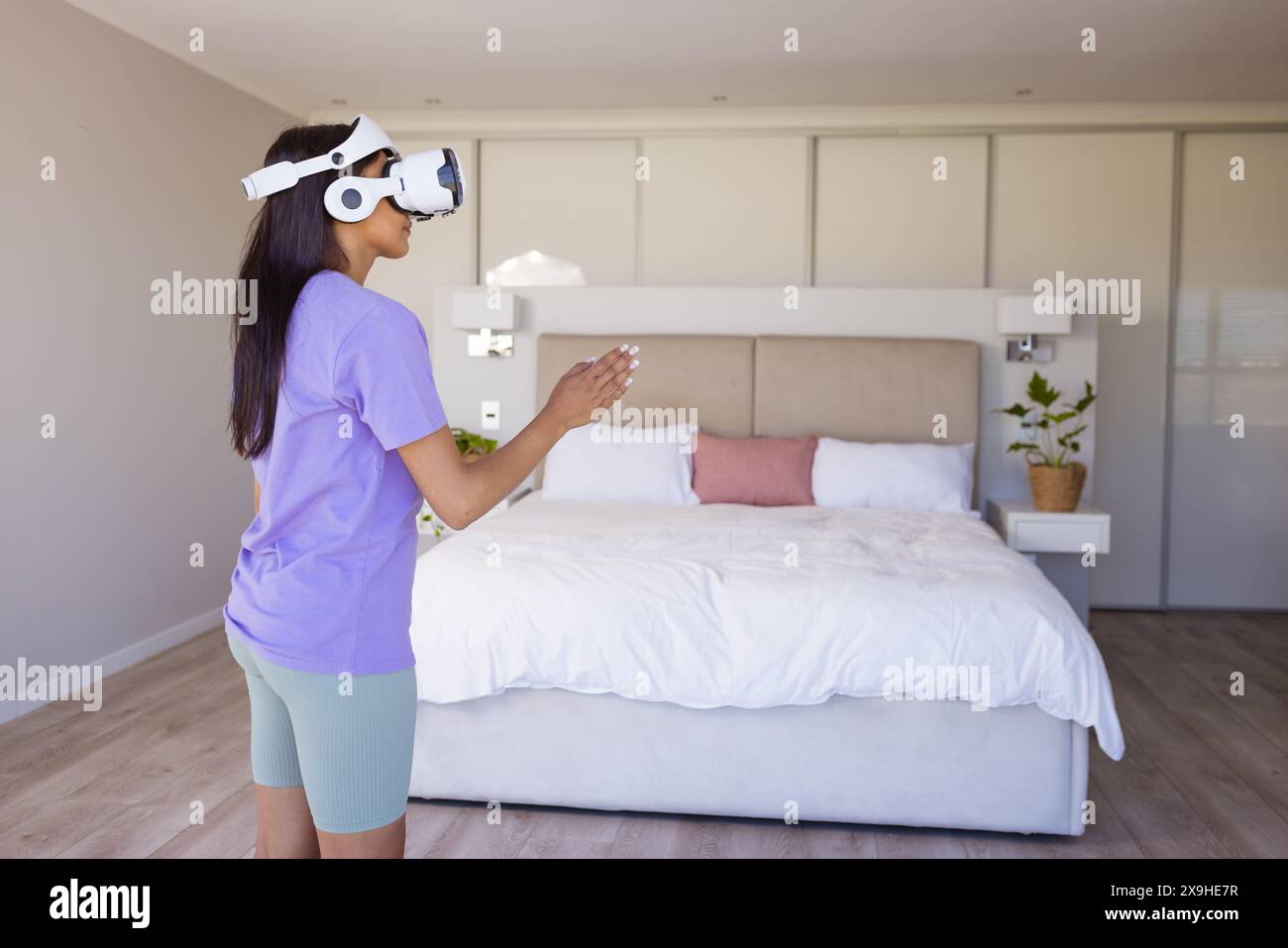 Una giovane donna birazziale che indossa un visore per la realtà virtuale a casa Foto Stock