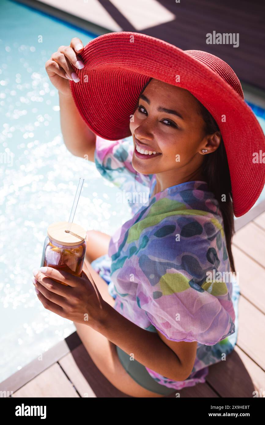 Una giovane donna birazziale che indossa un cappello rosso e si rilassa all'aperto Foto Stock