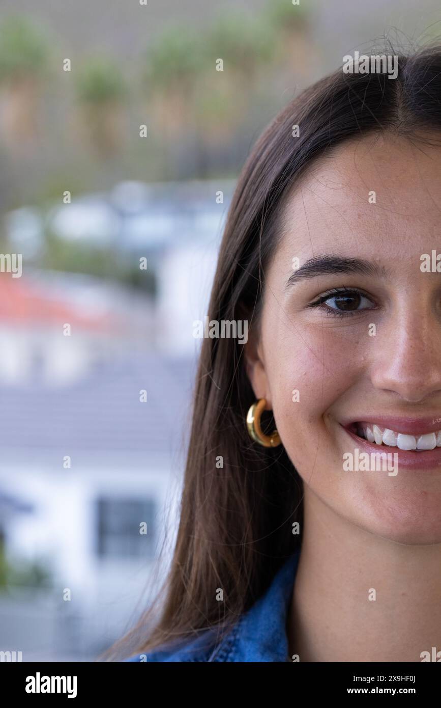 A casa, giovane donna caucasica con lunghi capelli marroni sorridente calorosamente, copia spazio Foto Stock