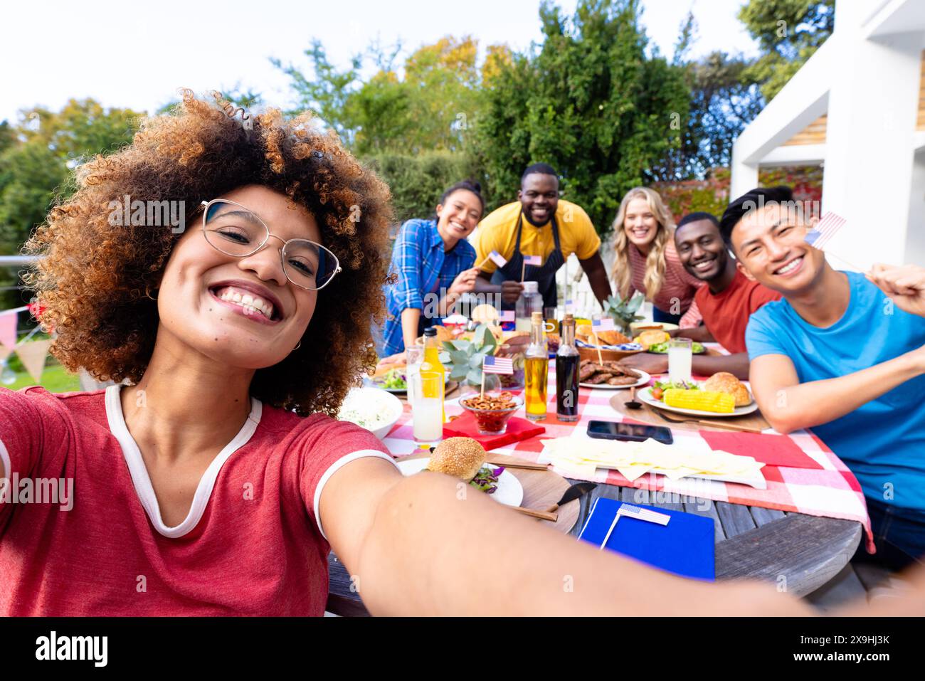 Ritratto di un gruppo di amici felici e diversi che fanno selfie e cenano con le bandiere degli stati uniti Foto Stock