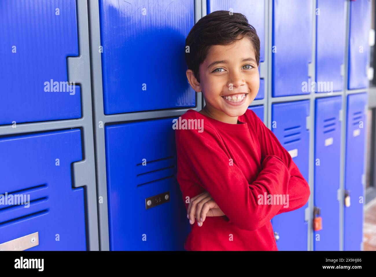 A scuola, all'aperto, il giovane studente birazziale maschile è in piedi, sorridente Foto Stock