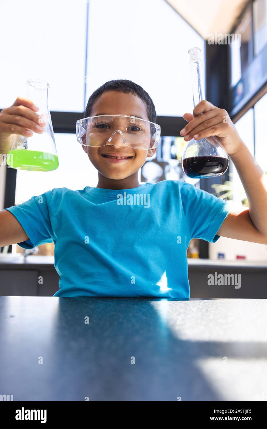 Un ragazzo birazziale conduce un esperimento scientifico a scuola in classe Foto Stock