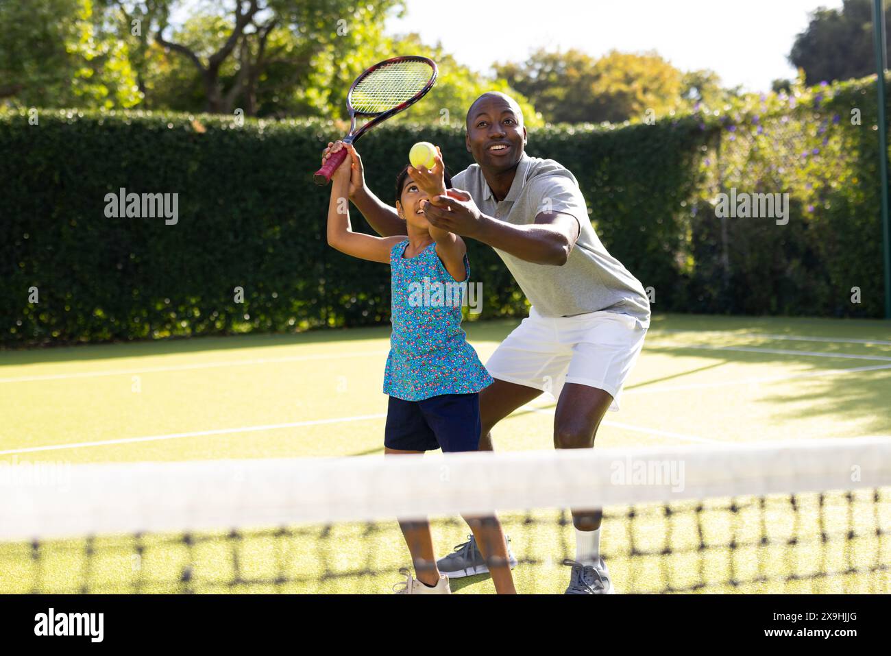 All'aperto, padre e figlia diversi giocano a tennis nelle giornate di sole Foto Stock