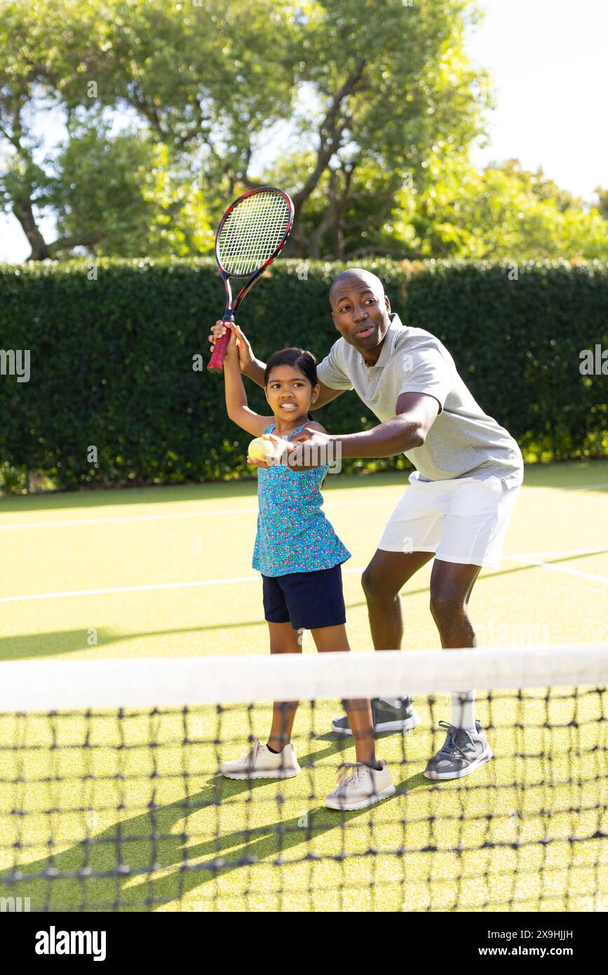 All'aperto, padre e figlia diversi giocano a tennis nelle giornate di sole Foto Stock