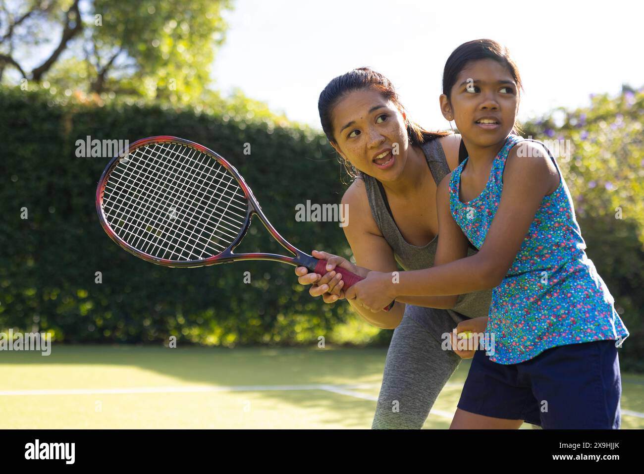 All'aperto, madre e figlia birazziali giocano a tennis nelle giornate di sole Foto Stock