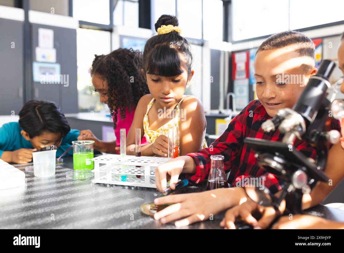 I bambini si impegnano in un esperimento scientifico a un tavolo in classe a scuola Foto Stock
