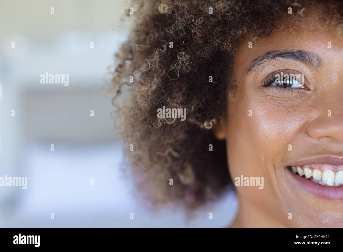 A casa, giovane donna birazziale che mostra i capelli ricci e gli occhi marroni, irradiando gioia, copiando spazio Foto Stock