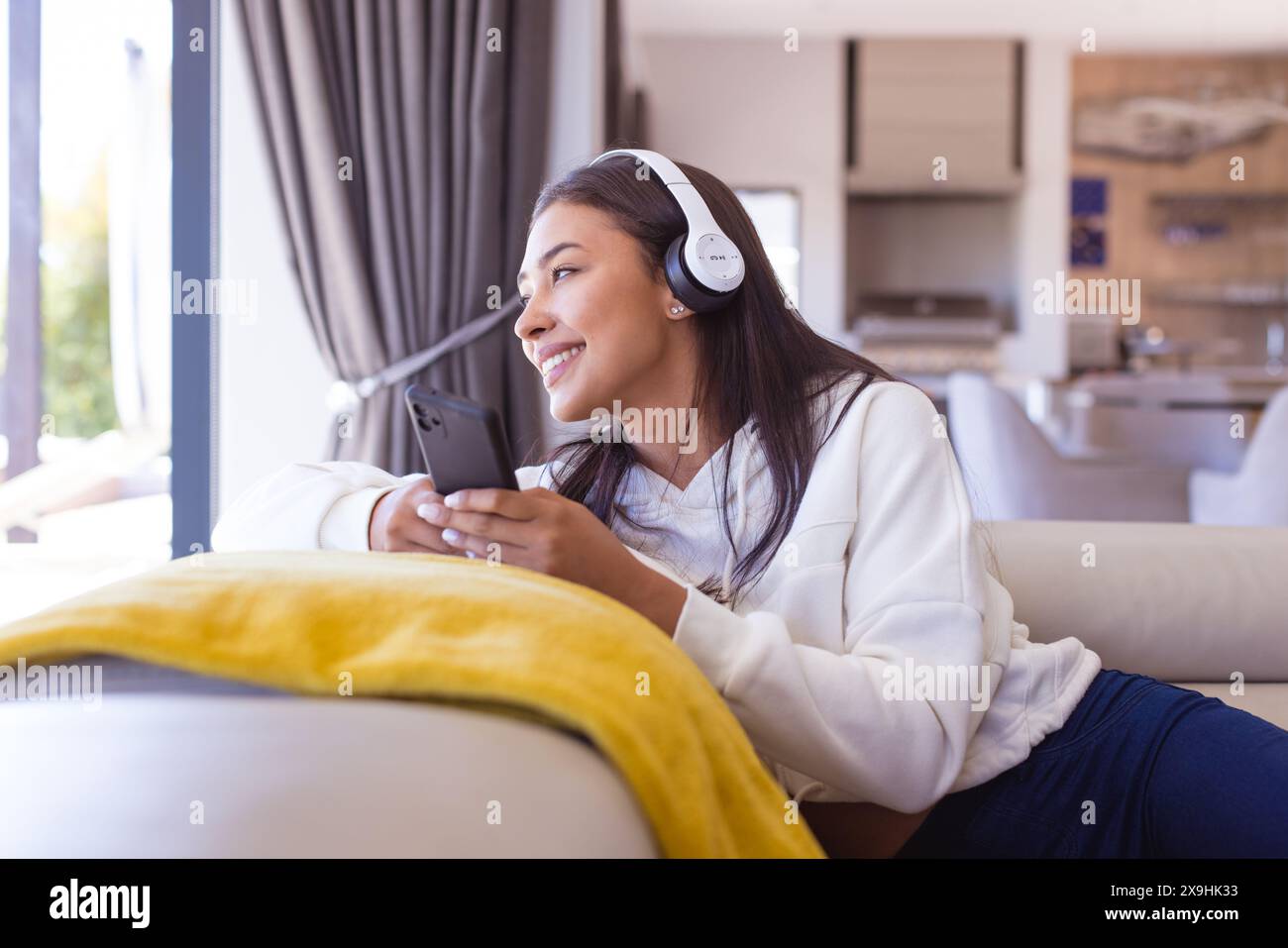 Una giovane donna birazziale che indossa le cuffie e si rilassa a casa Foto Stock