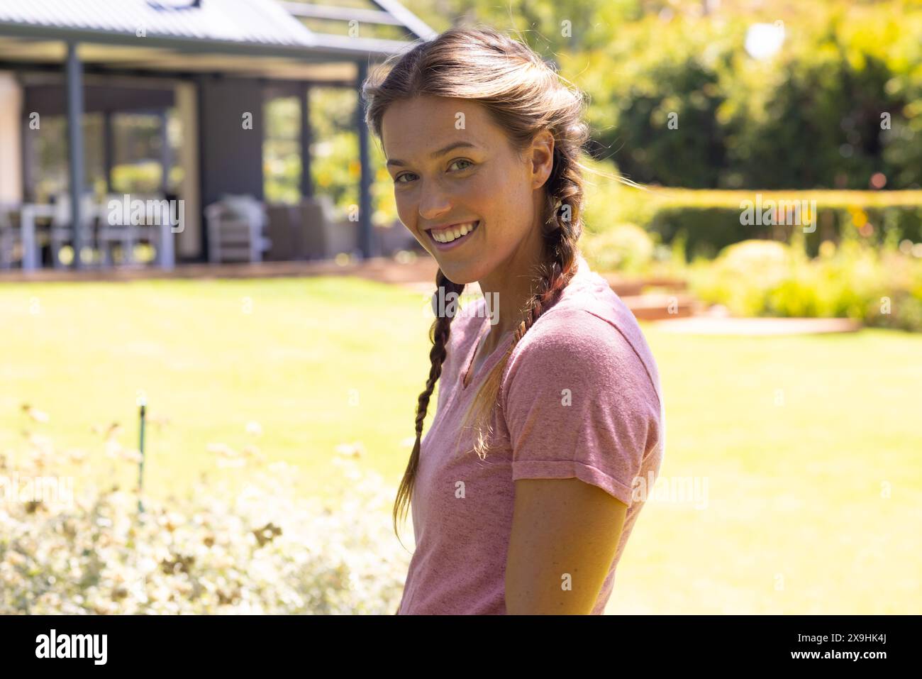 Una giovane donna caucasica che indossa una camicia rosa, sorride fuori Foto Stock