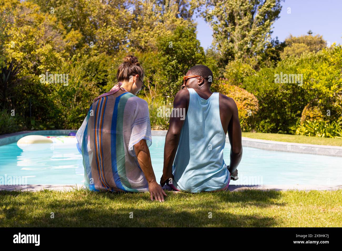 Una coppia giovane e variegata che si rilassa all'aperto vicino alla piscina Foto Stock