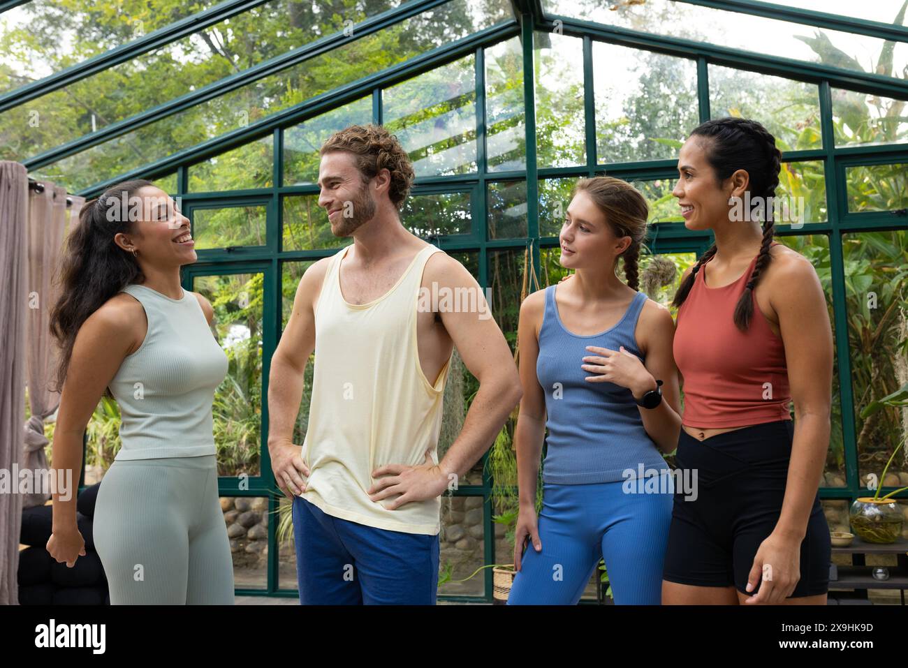 Studio in vetro che ospita diversi studenti di yoga che chiacchierano Foto Stock