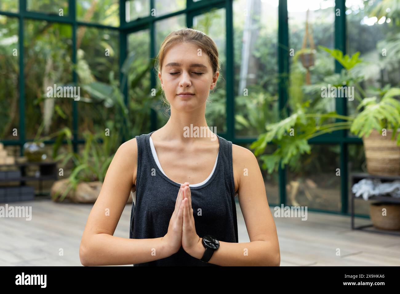 Lo studio in vetro mostra una donna caucasica in cima nera che meditava con gli occhi chiusi Foto Stock