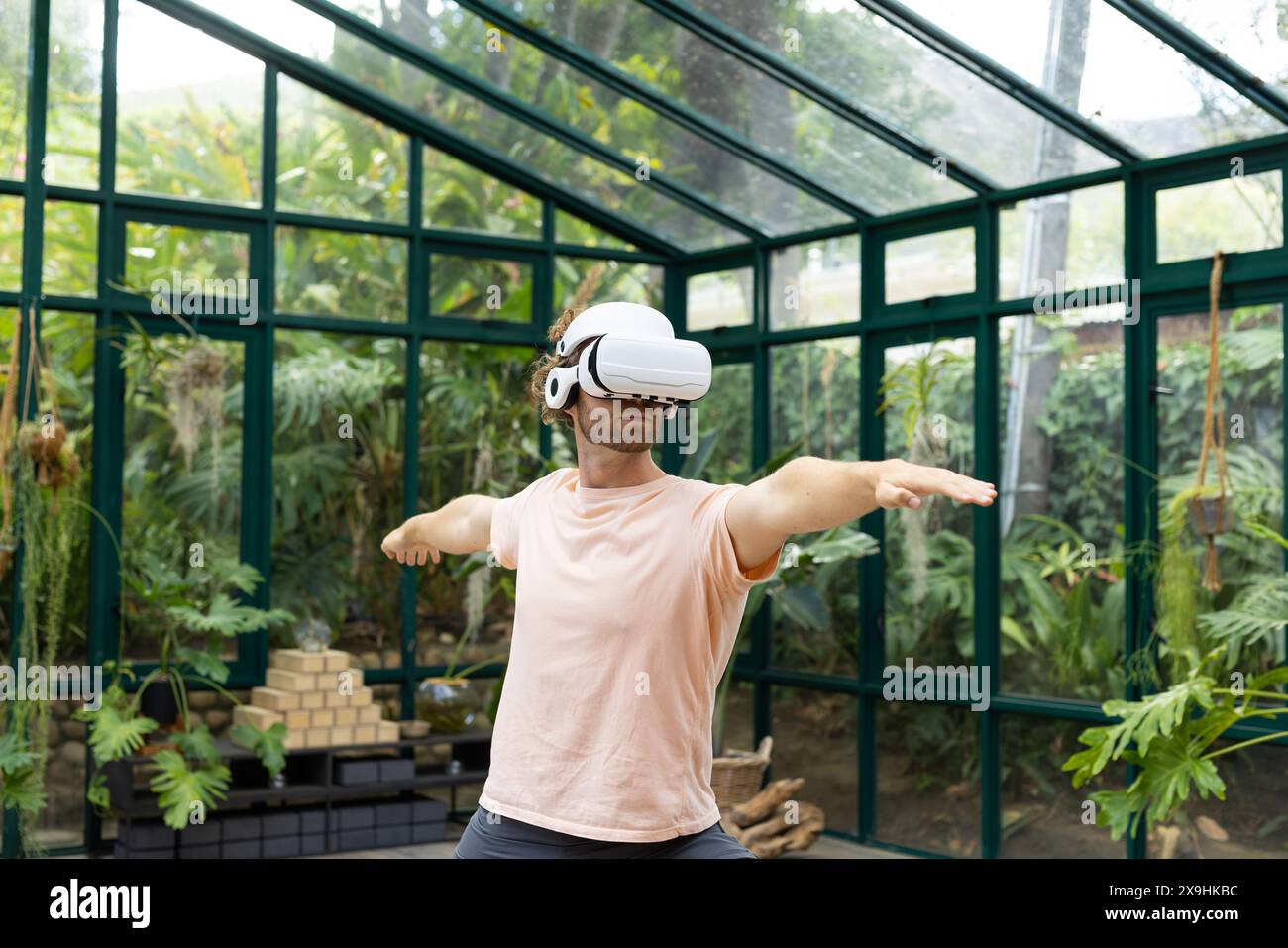 Istruttore di yoga maschile caucasico nelle pratiche con visore VR presso il Glass House Studio Foto Stock