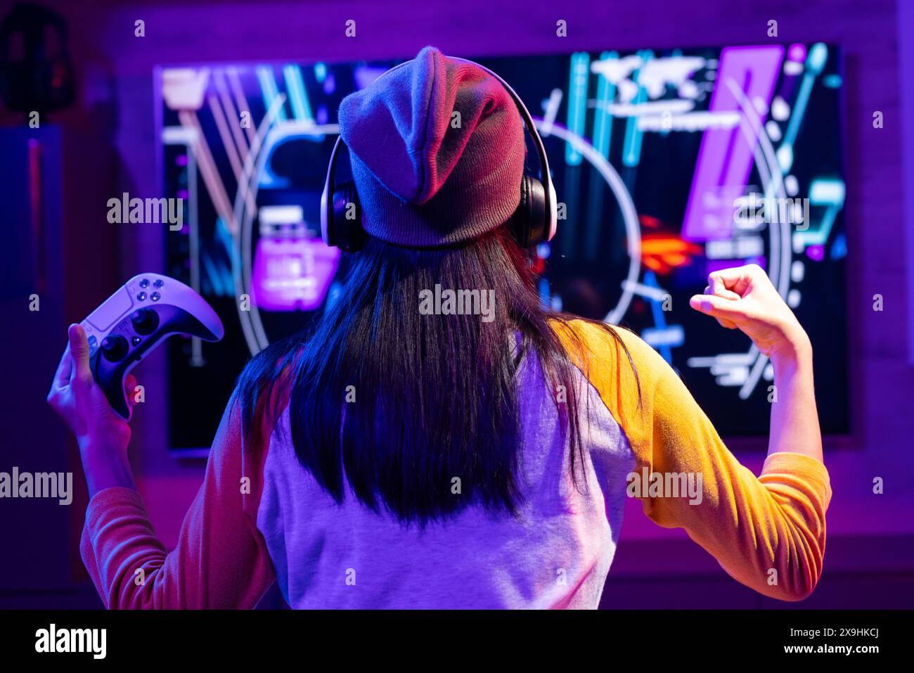 Una giovane ragazza birazziale che indossa le cuffie e gioca ai videogiochi a casa Foto Stock