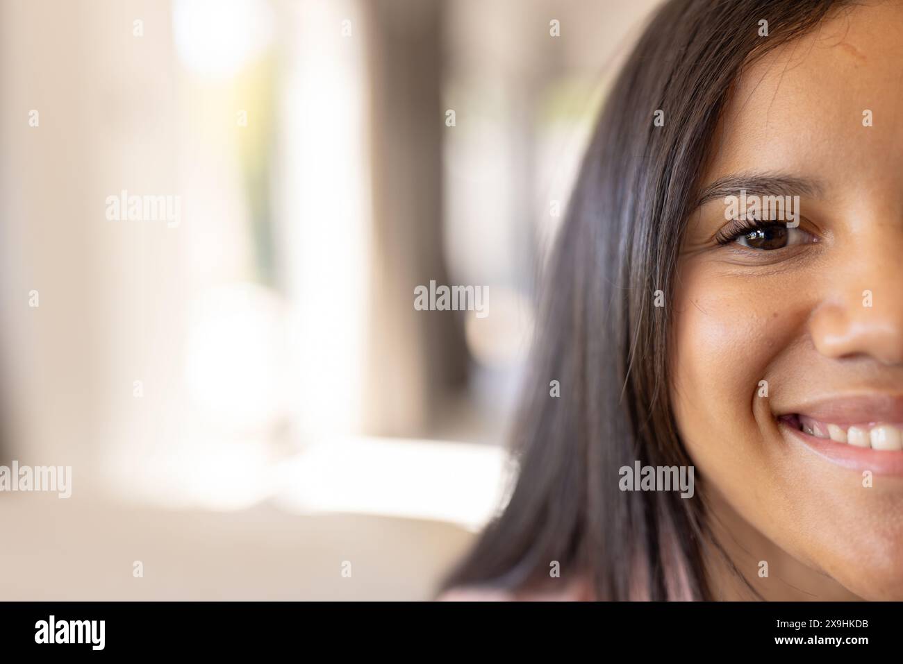 Una giovane ragazza birazziale a casa, indossa abiti casual, sorride dolcemente, copia spazio Foto Stock
