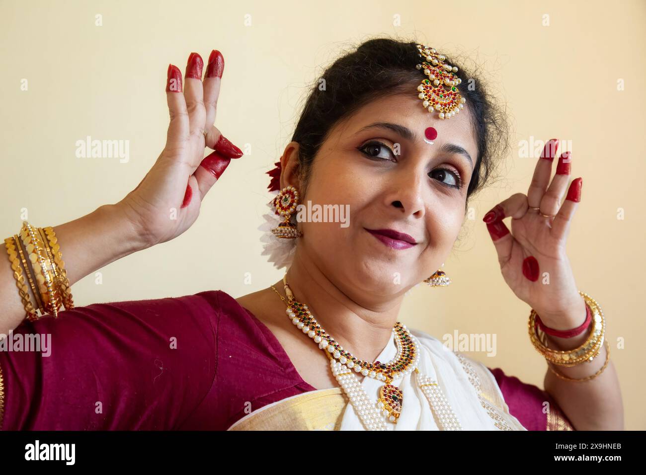 Ballerina classica indiana che dimostra la postura della danza classica di Bharatanatyam su sfondo chiaro Foto Stock