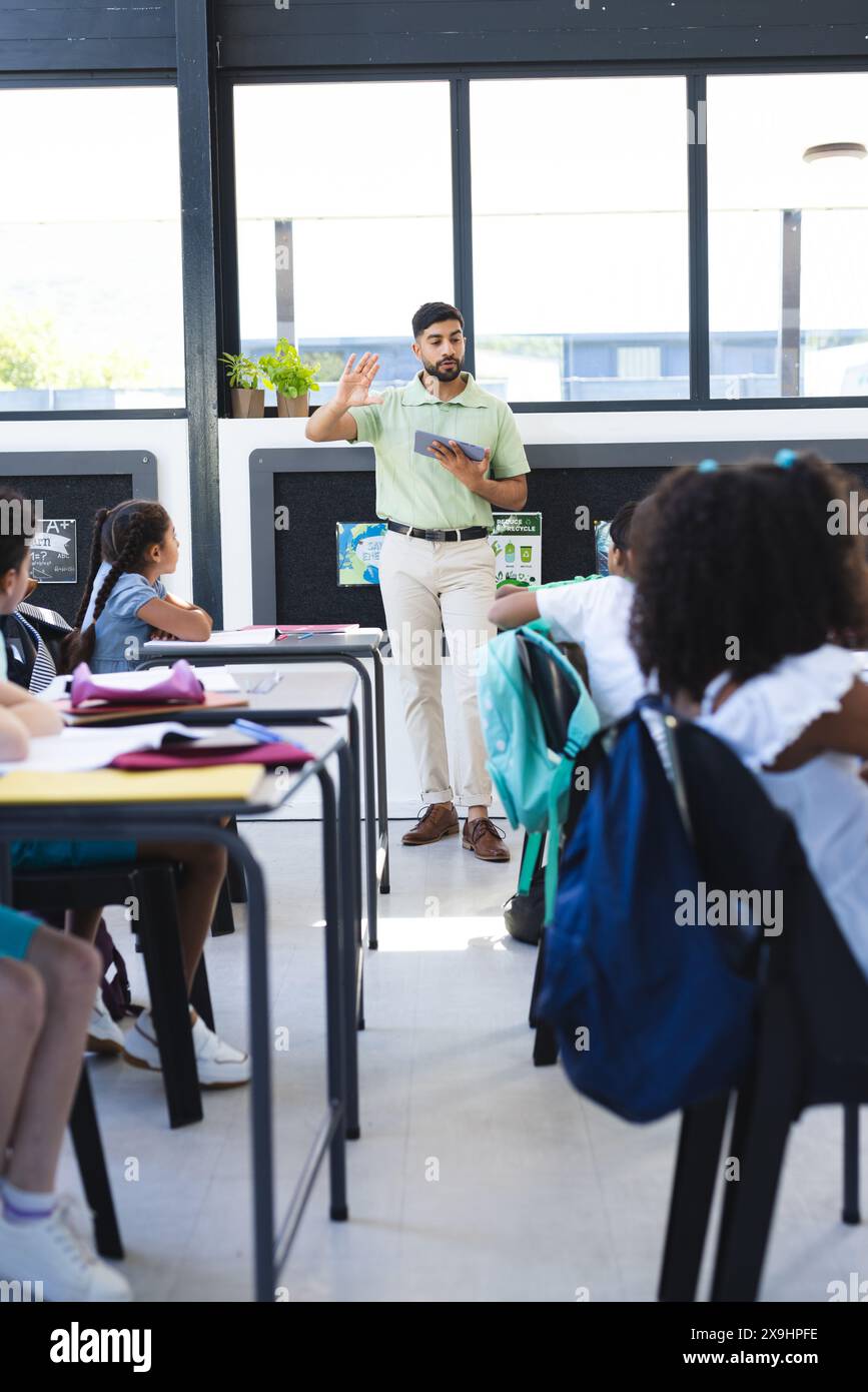 A scuola, un insegnante maschile asiatico sta spiegando agli studenti birazziali Foto Stock