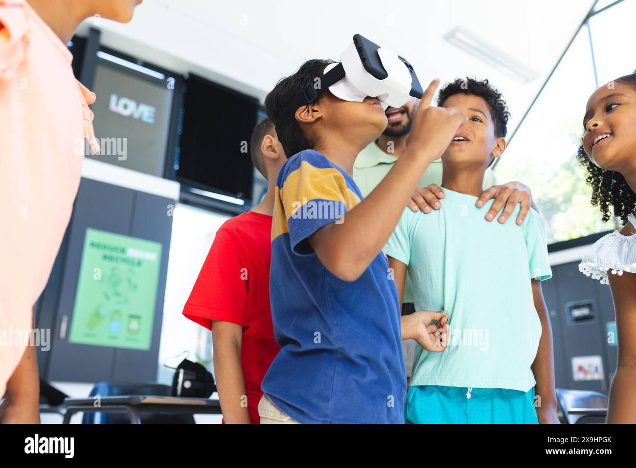 A scuola, diversi gruppi di giovani studenti stanno esplorando la realtà virtuale Foto Stock