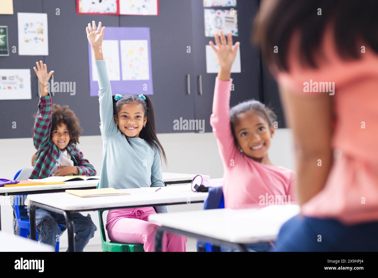 A scuola, una giovane donna birazziale insegna a tre giovani studenti in classe Foto Stock