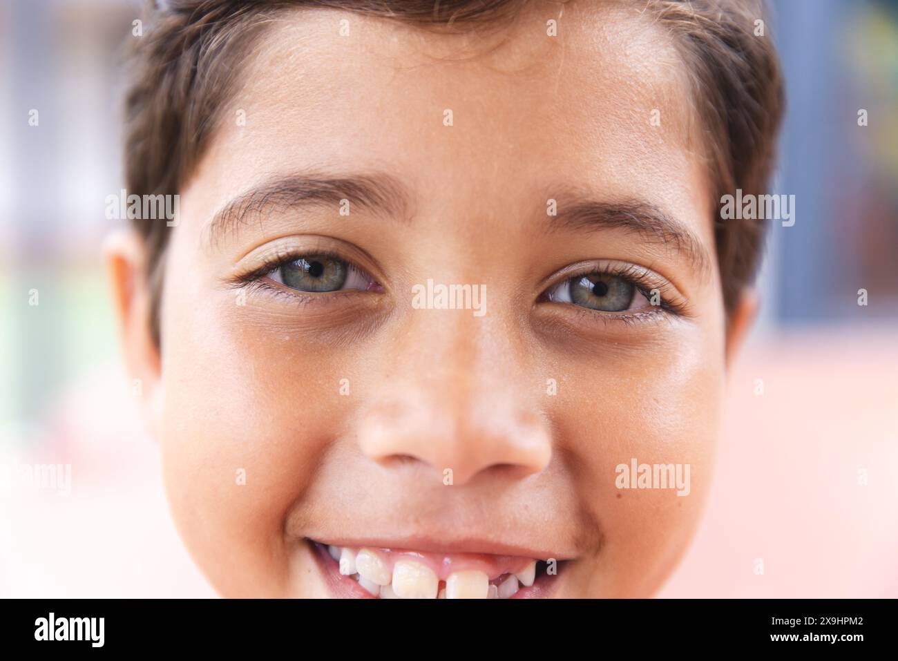 A scuola, il giovane studente birazziale maschile sorride alla telecamera all'aperto Foto Stock