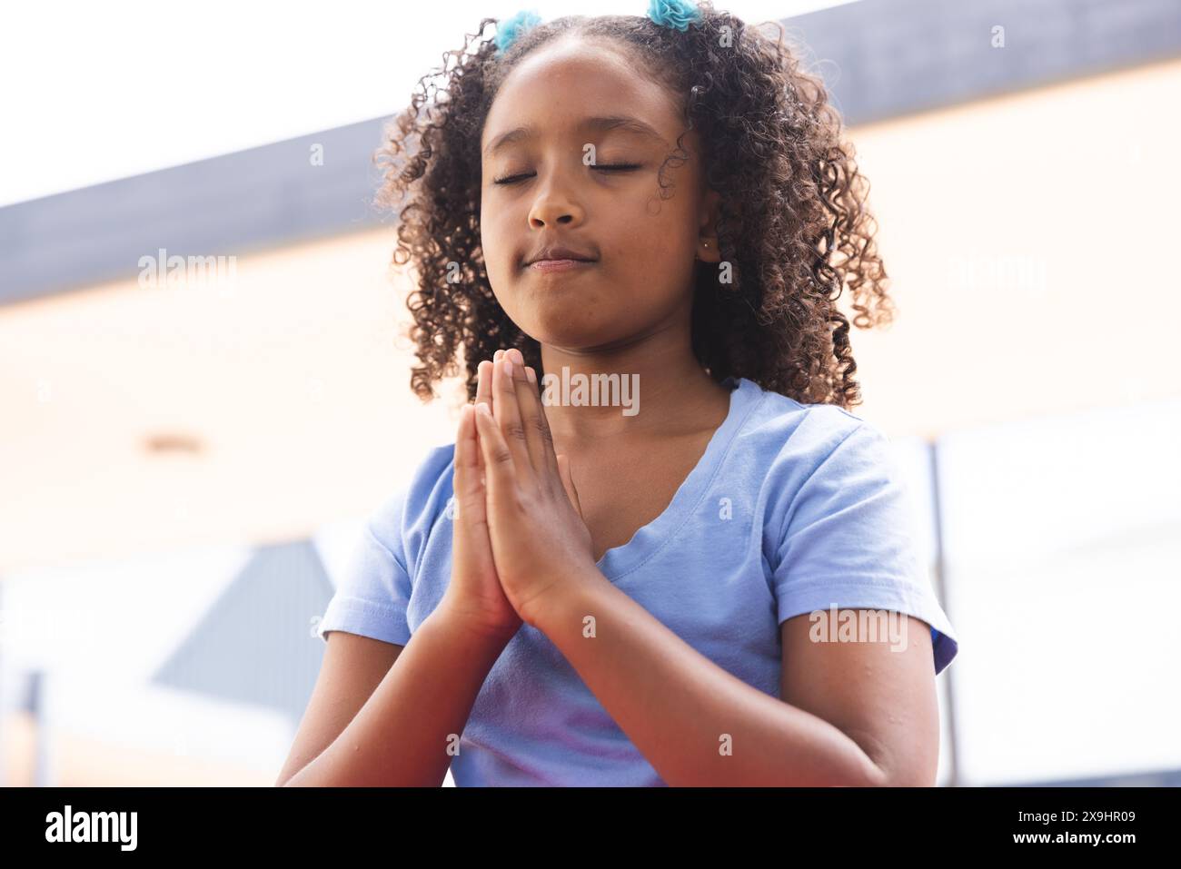 La ragazza birazziale pratica yoga all'aperto a scuola Foto Stock