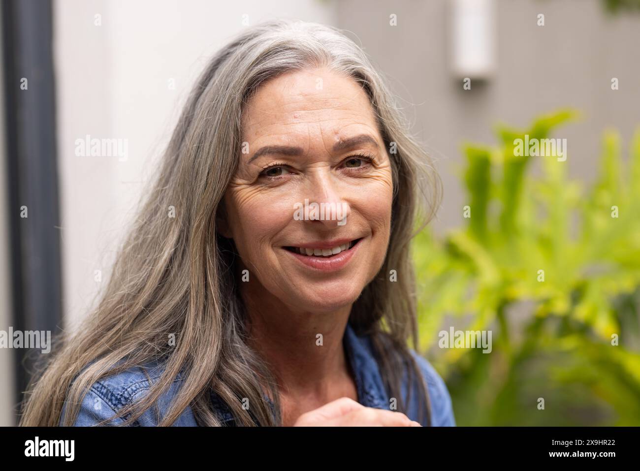 A casa, donne birazziali senior di mezza età con lunghi capelli grigi e rughe sorridenti all'aperto Foto Stock