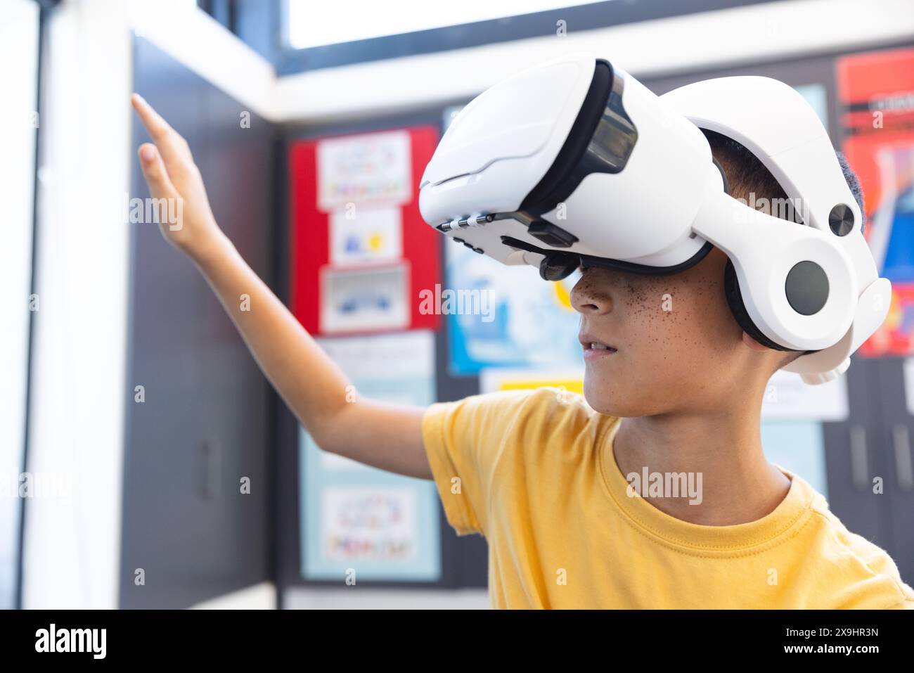 Il ragazzo birazziale esplora la realtà virtuale in un ambiente scolastico Foto Stock