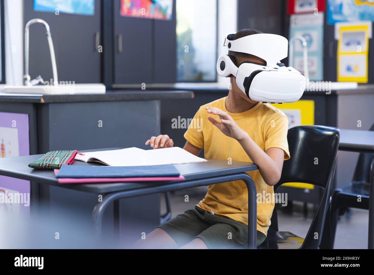 Il ragazzo birazziale esplora la realtà virtuale in una classe a scuola Foto Stock