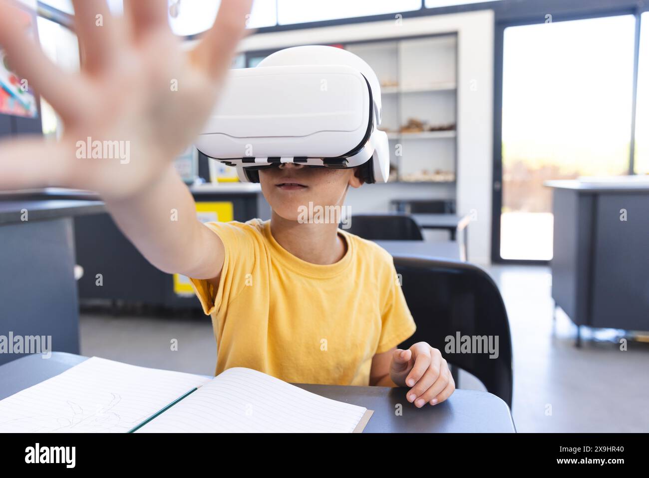 Birazziale ragazzo esplora la realtà virtuale a scuola Foto Stock