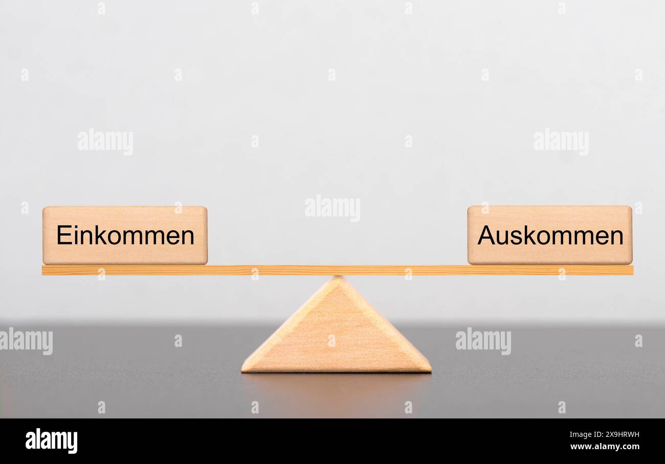 Einkommen und Auskommen im Gleichgewicht Zwei Holzwürfel mit der Aufschrift Einkommen und Auskommen liegen auf einer Wippe im Gleichgewicht *** reddito Foto Stock