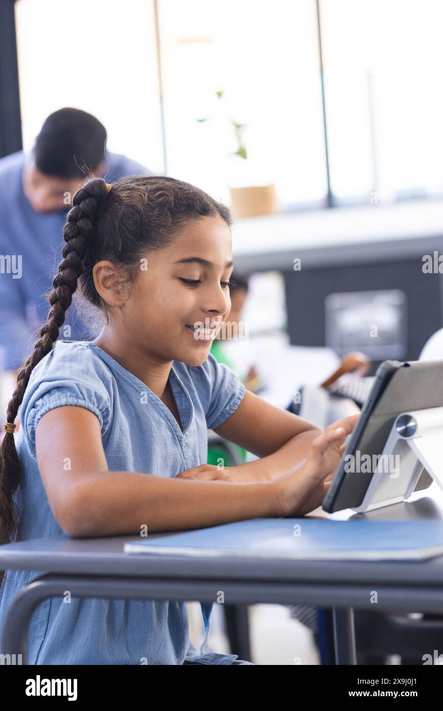 Una ragazza birazziale con treccia usa un tablet in classe per imparare Foto Stock