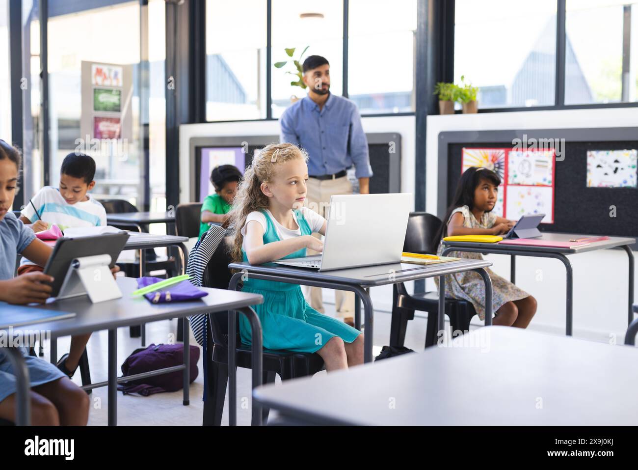 A scuola, in classe, un gruppo eterogeneo di giovani studenti si concentra sui loro notebook Foto Stock