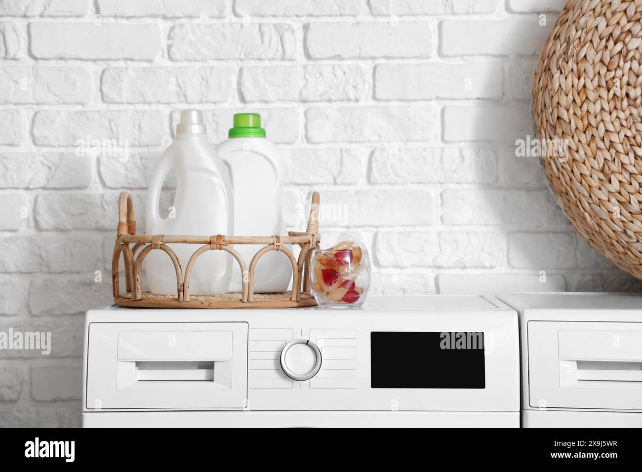 Bottiglie e capsule di detersivo per bucato su lavatrice, primo piano Foto Stock