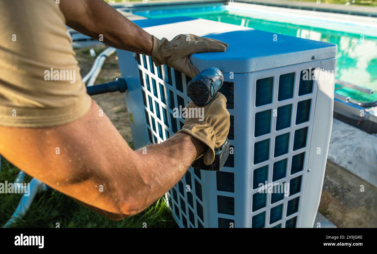 Tecnico HVAC che installa il riscaldatore della piscina vicino alla piscina Foto Stock