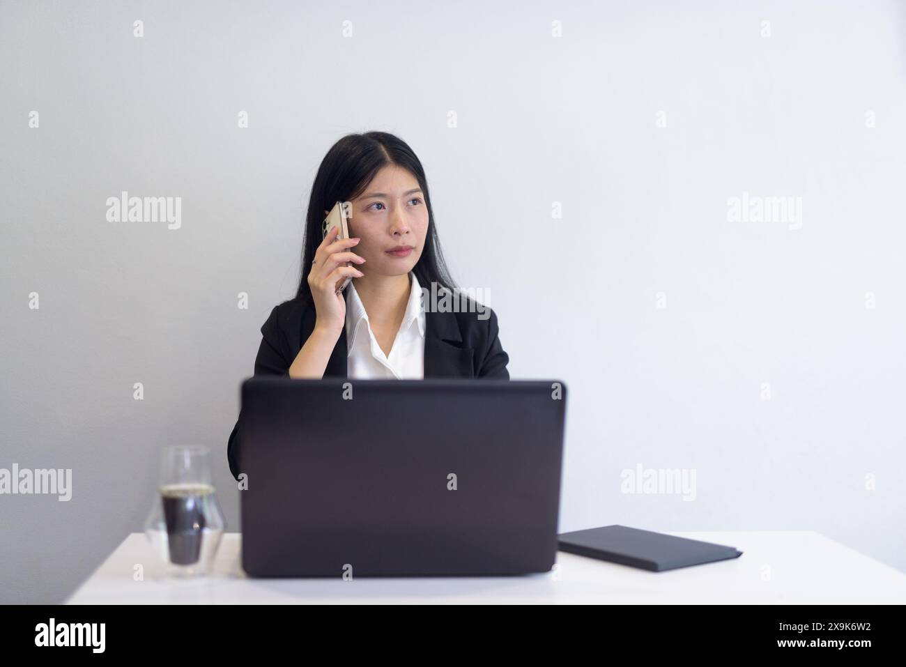 Donna d'affari asiatica con computer portatile che lavora in ufficio, caffè e notebook sulla scrivania. Impostazione professionale su sfondo bianco con spazio di riproduzione. Foto Stock