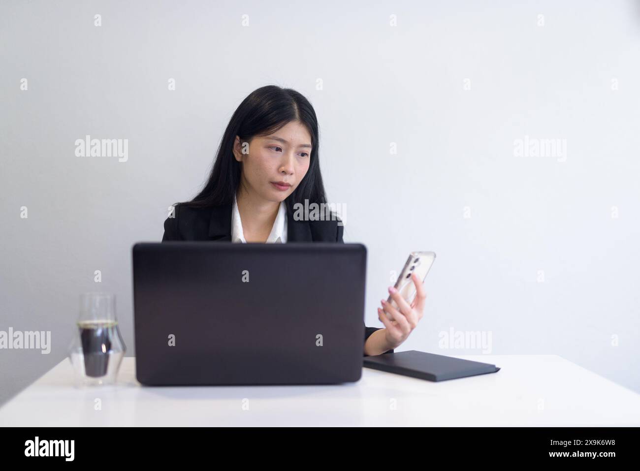 Donna d'affari asiatica con computer portatile che lavora in ufficio, caffè e notebook sulla scrivania. Impostazione professionale su sfondo bianco con spazio di riproduzione. Foto Stock