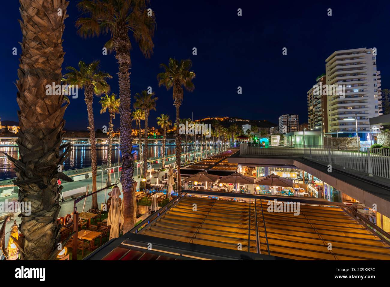 Paesaggio urbano di Malaga con il molo di Málaga, passerella lungo la baia del porto con ristoranti e edifici della città al tramonto. Paesaggio panoramico di Malaga, Spagna. Foto Stock