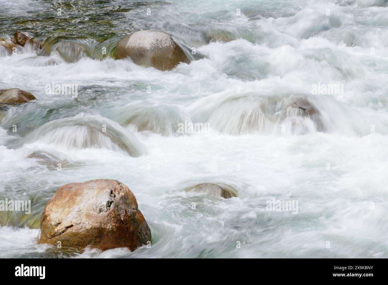 L'acqua turbolenta e pulita del fiume si schianta sulle rocce lisce del fiume creando acqua bianca durante la discesa Foto Stock