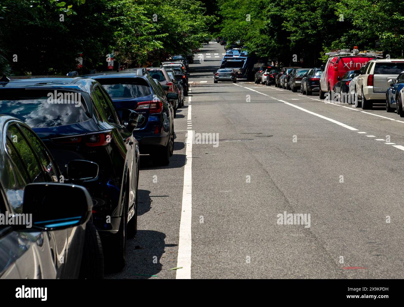 Una lunga linea retta di auto parcheggiate in modo ordinato Foto Stock