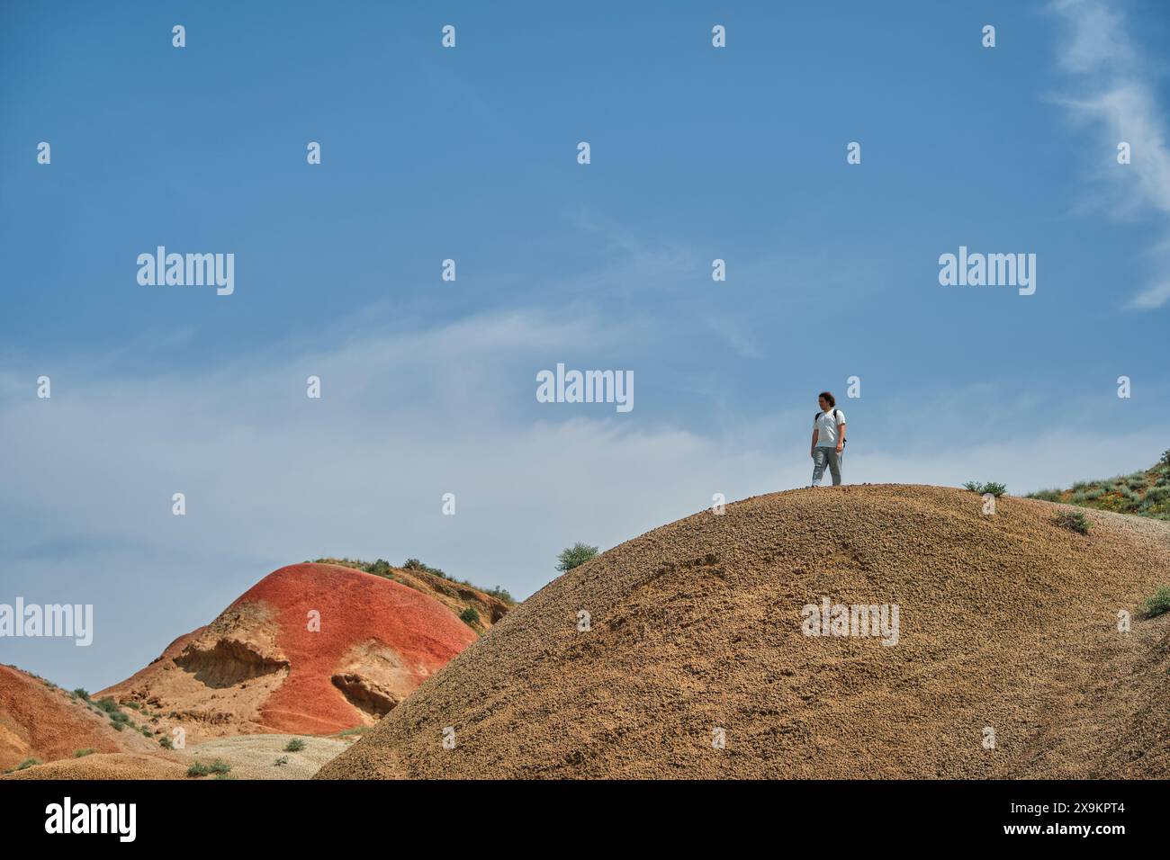 Magnifico paesaggio delle colline rosse della Georgia, un giovane uomo su un'alta cresta contro il cielo blu, un poster per tour pubblicitari con spazio per le copie Foto Stock