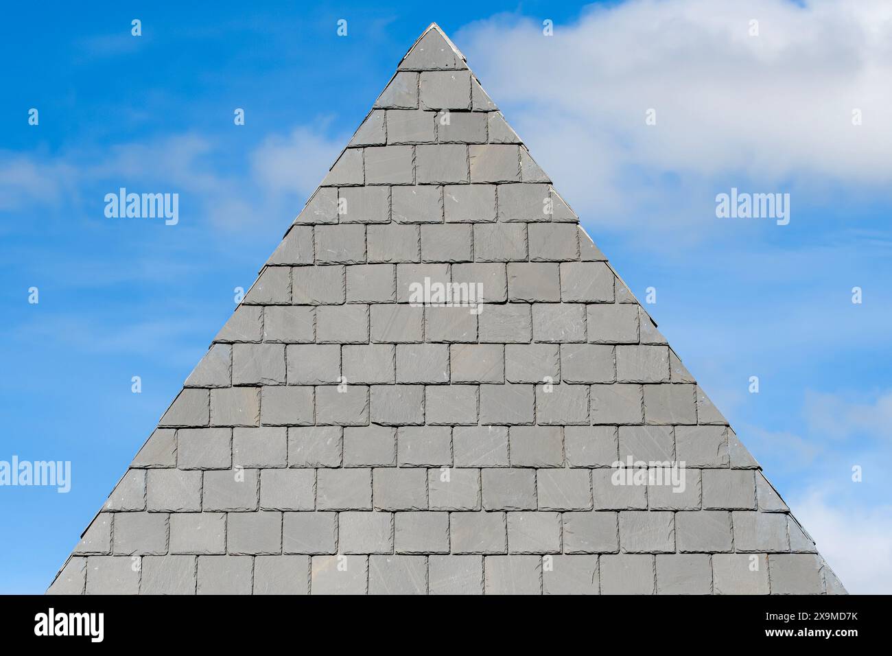 Un primo piano di una piramide costruita da pietre ben tagliate. Cielo blu con nuvole sopra. Foto Stock